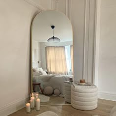 a mirror sitting on top of a wooden floor next to a white couch and pillows