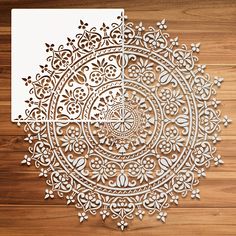 an intricate laser cut design with white paper on wooden floor and wood paneled wall