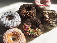 six donuts with sprinkles are arranged on a white tablecloth,