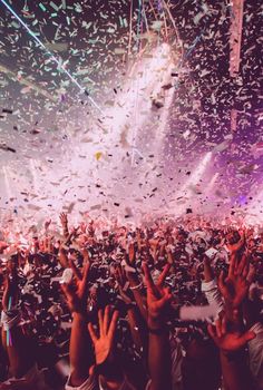 a large group of people at a concert with confetti falling from the ceiling