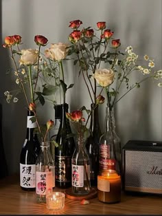 several bottles with flowers in them on a table next to candles and a radio player