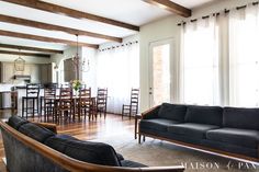 a living room filled with furniture next to a kitchen and dining room table on top of a hard wood floor