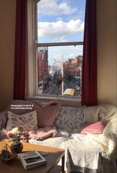 a living room filled with furniture and a large window overlooking the street below it's red curtains