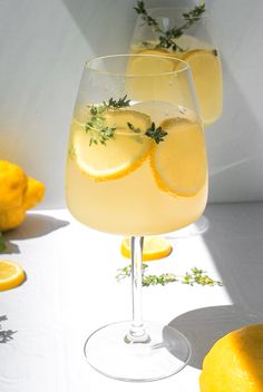 two glasses filled with lemonade sitting on top of a table next to lemons