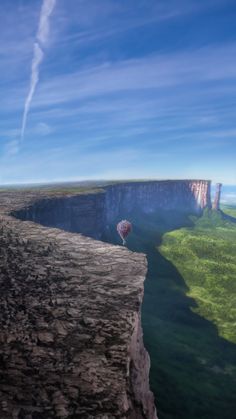 a hot air balloon flying over the edge of a cliff