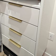 a white dresser with gold handles and drawers