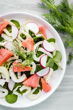 a white bowl filled with watermelon, radishes and cucumbers