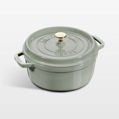 a green casserole with a gold knob on the top and bottom, sitting in front of a white background