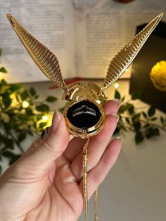 a person is holding a gold bird brooch with a black stone in it's center