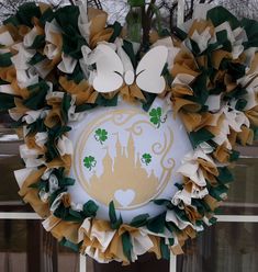 a wreath that is hanging on the side of a window with green and white decorations