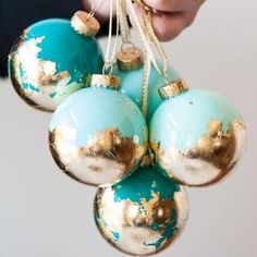 three blue and gold ornaments hanging from a white ceiling fixture with twinklings on each ornament