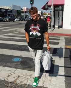 a man is walking across the street with shopping bags in his hand and smiling at the camera