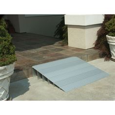 a metal ramp sitting on the side of a building next to potted plants and trees