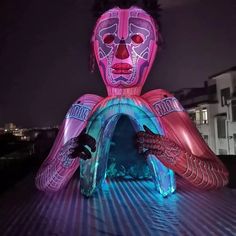 an inflatable figure is lit up with blue and pink lights on it's face