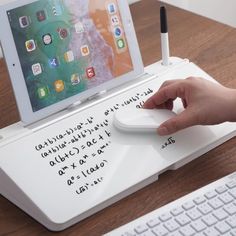 a person using a mouse and keyboard to write on an ipad with writing on it