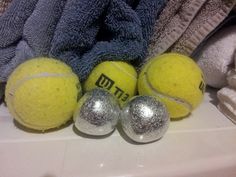 three tennis balls sitting next to each other on top of a white surface with towels in the background