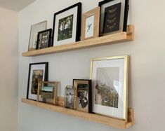 three wooden shelves with pictures and framed photographs on them