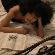 a woman laying in bed with an open book next to her head and hand on the pillow