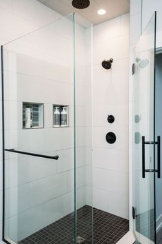 a glass shower door in a bathroom with black and white tile on the floor,