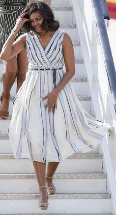 a woman in a white dress is walking down the stairs