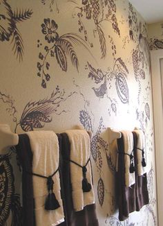 towels are hanging on the wall in front of an ornate wallpapered room with floral designs