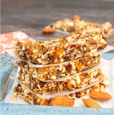 a stack of granola bars sitting on top of a blue plate next to almonds