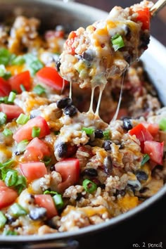 a spoon full of mexican rice salad with black olives and tomatoes on the side