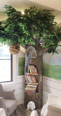 there is a tree with books on it in the corner of this room, next to two chairs and a book shelf