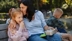 a woman and two children sitting on a bench