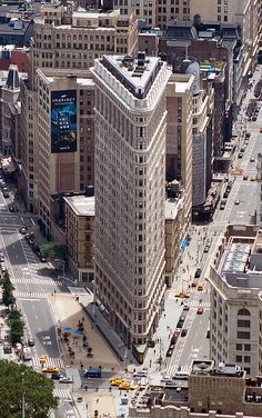 an aerial view of a city with tall buildings and cars driving down the street in front of them