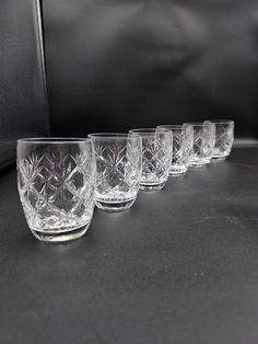 five glasses are lined up on a black counter top, with one empty glass in the middle