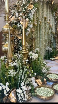 an elaborately decorated table with candles, flowers and greenery in gold dishes on it