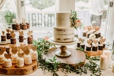 a table topped with lots of cakes and cupcakes on top of wooden slices