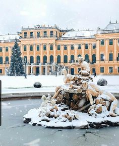 a fountain in front of a large building covered in snow