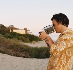 a man holding an old camera on the beach