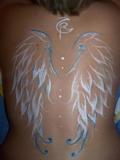 the back of a woman's body with white and blue wings painted on it