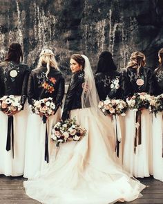 a group of bridesmaids standing in front of a waterfall with their bouquets