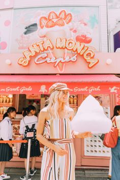 a woman standing in front of a store holding a large white item with the word santa monica on it