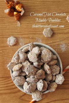 a bowl filled with marshmallows sitting on top of a wooden table next to an orange and white striped straw