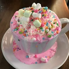 a cup filled with marshmallows and sprinkles on top of a white plate