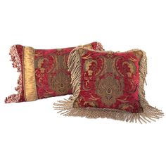 two red and gold pillows with tassels on the sides, one has an intricate design