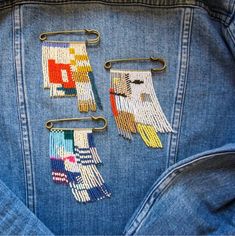 the back of a jean jacket with embroidered patches on it and two clips attached to them