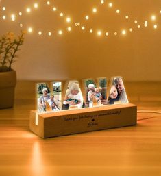 a wooden block with four photos on it and string lights in the background, along with a potted plant