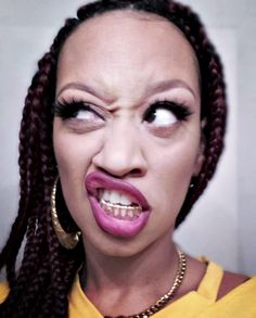 a woman with long braids and pink lipstick making a funny face to the camera