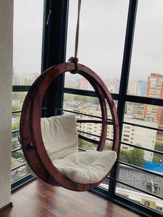 a swing chair hanging from the side of a window in a room with large windows