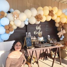 a woman sitting in front of a table filled with balloons