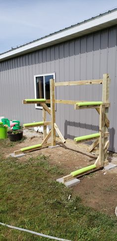 an unfinished wooden fence in front of a building with green hoses attached to it