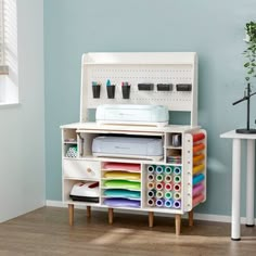 a white desk with lots of crafting supplies on it and a window in the background