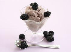 a scoop of ice cream with blackberries in it and spoons on the side