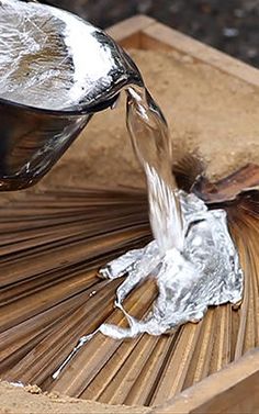 a wooden box with some tin foil on it and a spoon pouring water into it